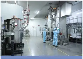 Technicians in cleanroom suits operating electrode mixing equipment